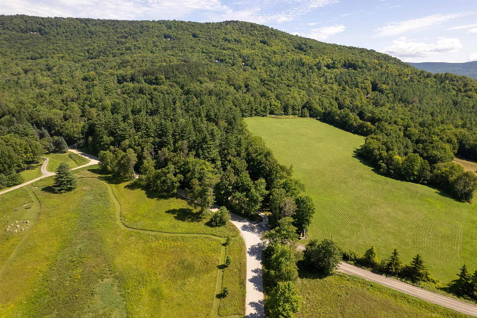 An aerial view of green fields, winding country roads, and wooded hills around Rochester